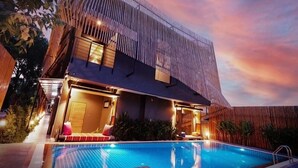 A modern building with a pool, wooden exterior, and warm lighting. - Sand Dollar Boutique Hotel (Sattahip)