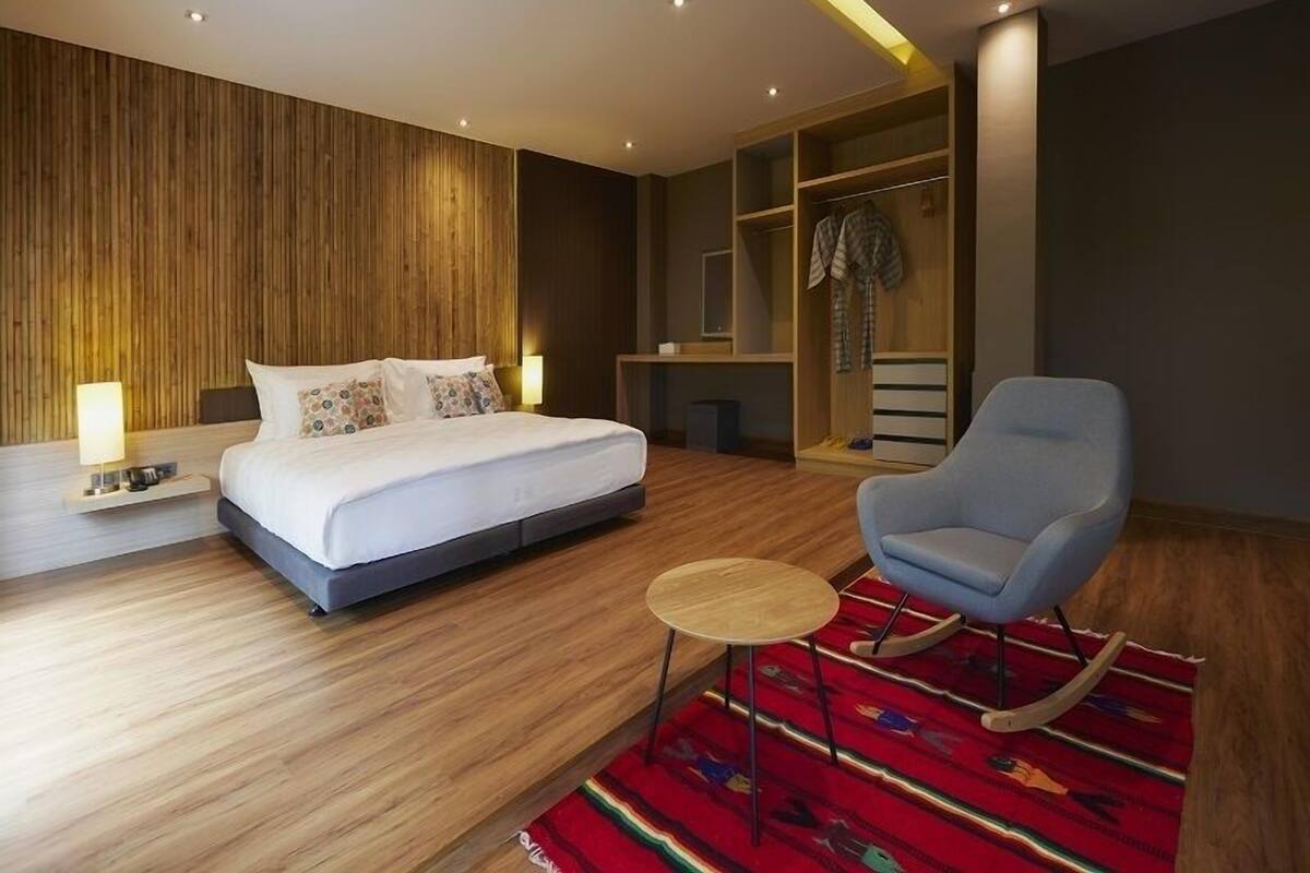 A modern bedroom with a bed, bedside table, chair, and a wardrobe.