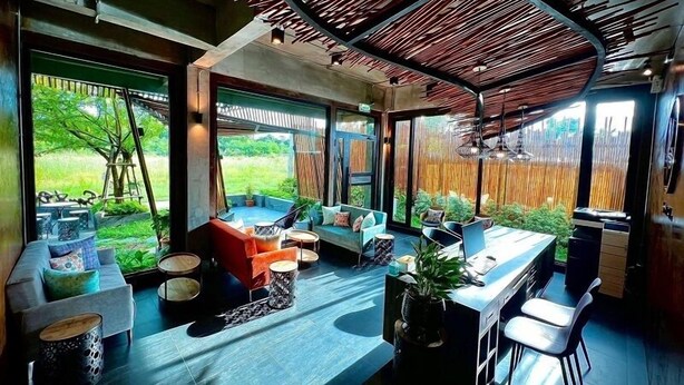 A modern interior with a curved ceiling, large windows, and a seating area with a view of the outdoors. - Sand Dollar Boutique Hotel (Sattahip)