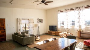 A living room with a sofa, TV, dining table, and chairs. - Eclectic, Art-filled Studio with Fantastic Views (El Prado)