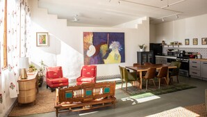 A spacious living area with a dining table, chairs, and a sofa. A kitchen is visible in the background with modern appliances. - Eclectic, Art-filled Studio with Fantastic Views (El Prado)