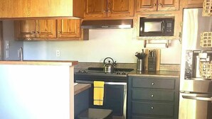 A kitchen with wooden cabinets, a microwave, a stove, and a refrigerator. - 15 Fisher's Paradise on Lake Saluda w Boat Ramp (Greenville)