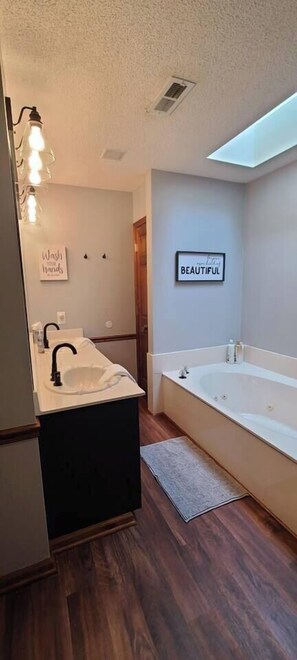 A modern bathroom with a sink, vanity, and bathtub. There are wall-mounted lights, a ceiling vent, and a motivational quote on the wall. - 15 Fisher's Paradise on Lake Saluda w Boat Ramp (Greenville)