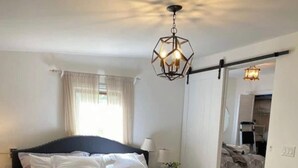 Une chambre à coucher avec un grand lit, une table de chevet, une lampe et un luminaire au plafond.