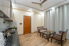 A modern kitchen with a built-in stove, a wooden door, and a dining area with a glass table and wooden chairs.