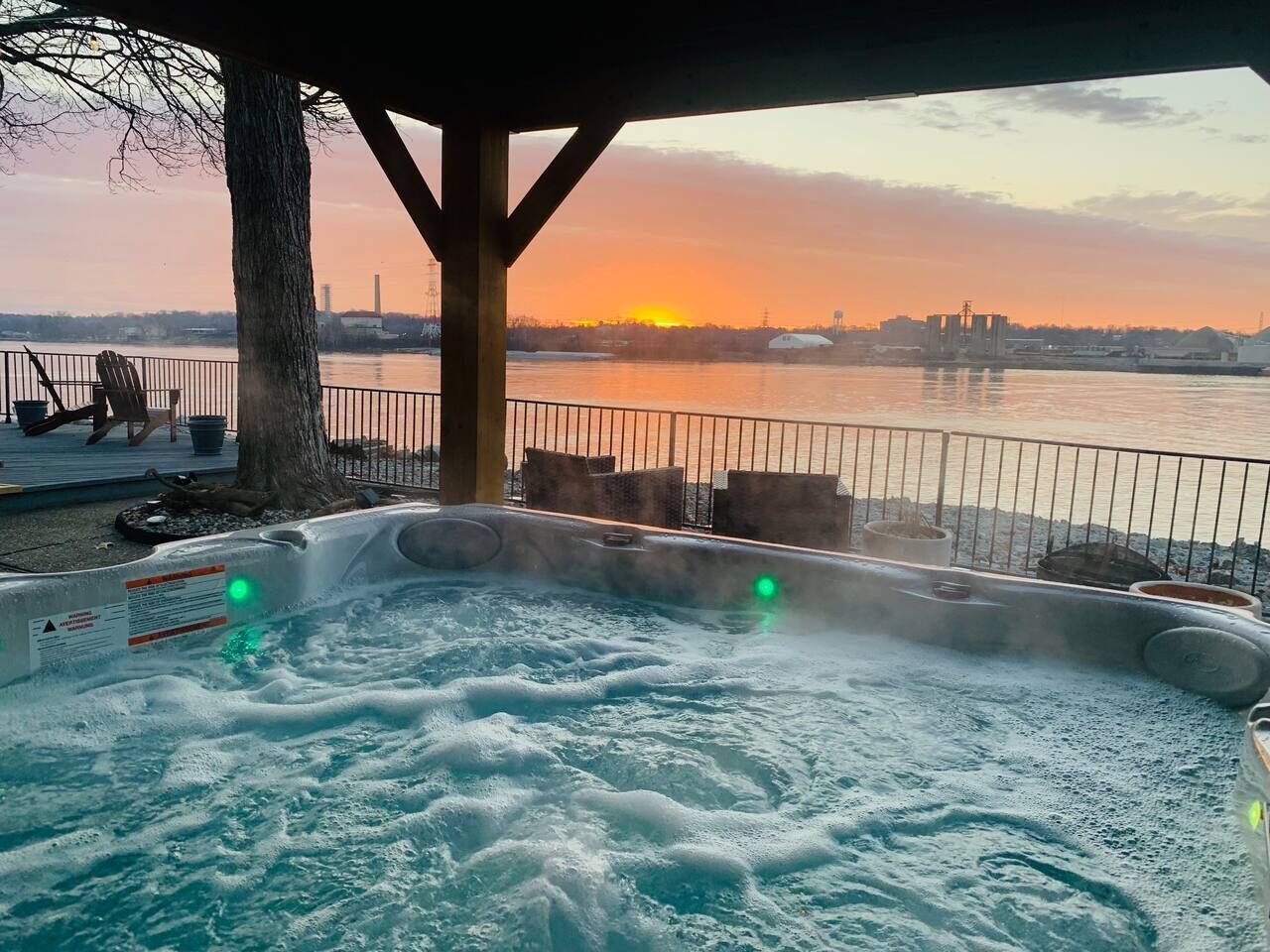 Un jacuzzi con vistas a un atardecer sobre un cuerpo de agua.