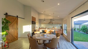A modern kitchen with a central island, pendant lighting, and a sliding glass door leading to a backyard. - Warm Safe Quiet Spacious Family Home, Sleeps 7 (Prebbleton)