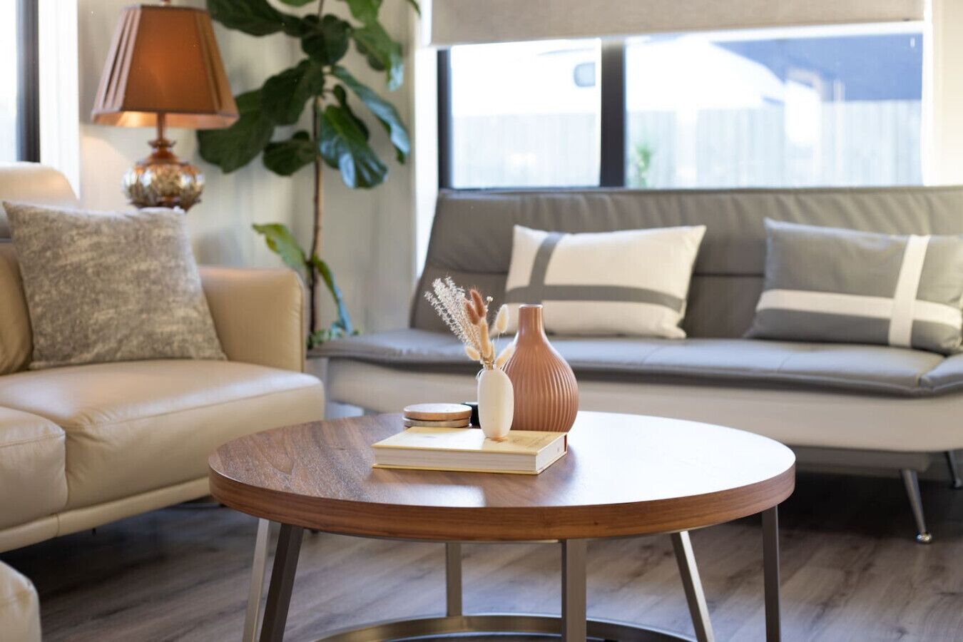 A living room with a round wooden coffee table, a sofa, and a lamp.