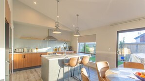 A modern kitchen with a central island, wooden cabinets, and pendant lighting. - Warm Safe Quiet Spacious Family Home, Sleeps 7 (Prebbleton)