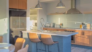 A modern kitchen with a central island, bar stools, and pendant lighting. - Warm Safe Quiet Spacious Family Home, Sleeps 7 (Prebbleton)