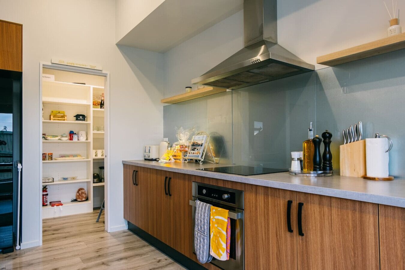 Una cocina moderna con armarios de madera, una campana extractora de acero inoxidable y un horno empotrado.