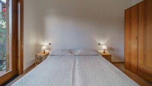 Un dormitorio con una cama grande, un armario de madera y dos lámparas de noche.