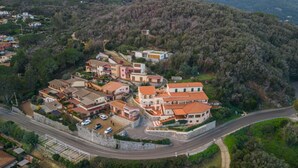Vista aérea de una zona residencial en una ladera, con casas, una carretera y un espacio verde.