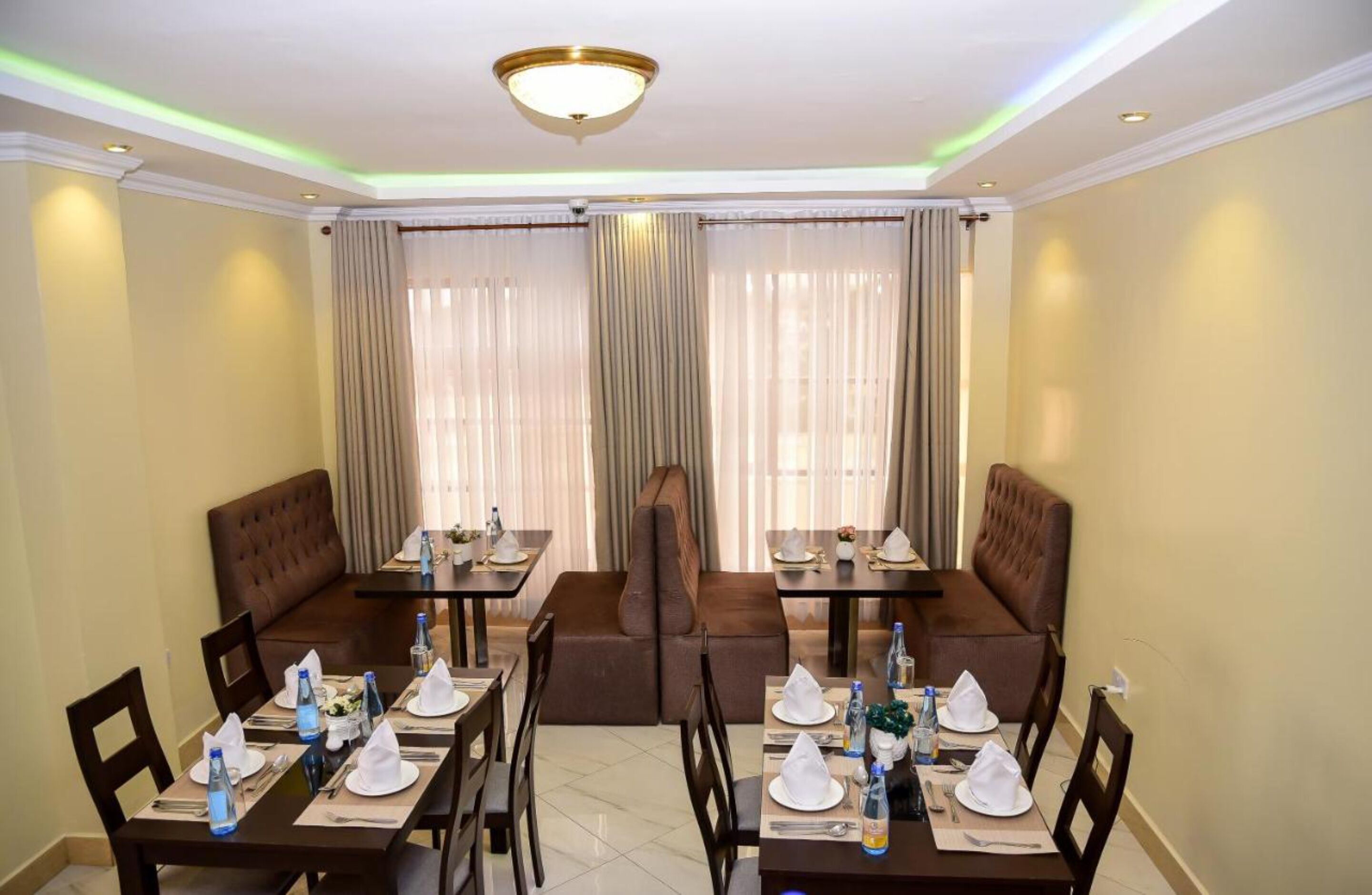 A dining area with tables set for four, each with a brown leather booth and white napkins.