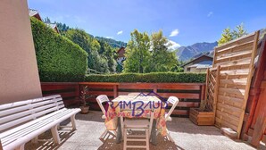 Eine Terrasse im Freien mit Tisch, Stühlen und einer Bank, begrenzt durch einen Holzzaun.