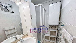 Ein Badezimmer mit Waschbecken, Spiegel, Handtuchhalter, Dusche und Toilette.
