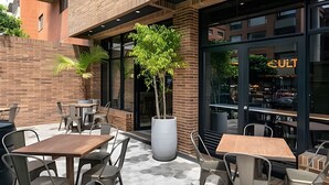 An outdoor cafe area with brick walls, large windows, and multiple tables and chairs. - Morph Chico (Bogotá)