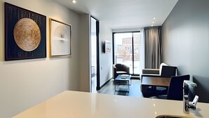 A modern hotel room with a large window, a dining area with a table and chairs, and two framed artworks on the wall. - Morph Chico (Bogotá)