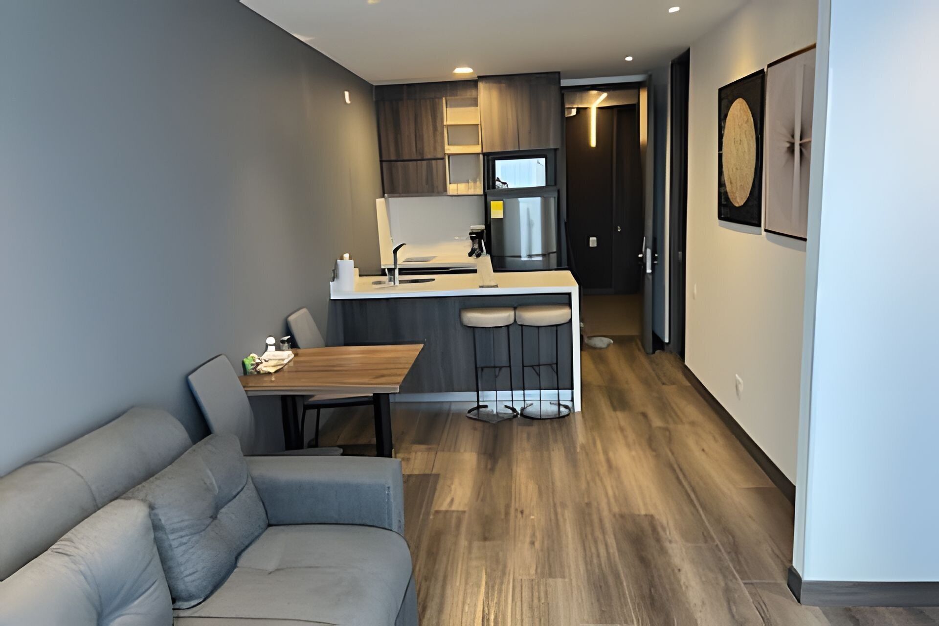 A modern kitchen with a dining area, a sofa, and a small bar counter.