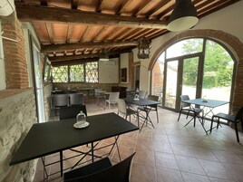 Un área de comedor al aire libre con mesas y sillas, una pared de piedra y un techo de madera.