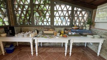 Un buffet de petit-déjeuner avec divers aliments et boissons disposés sur une table, le tout installé devant un mur de pierre et des poutres en bois.