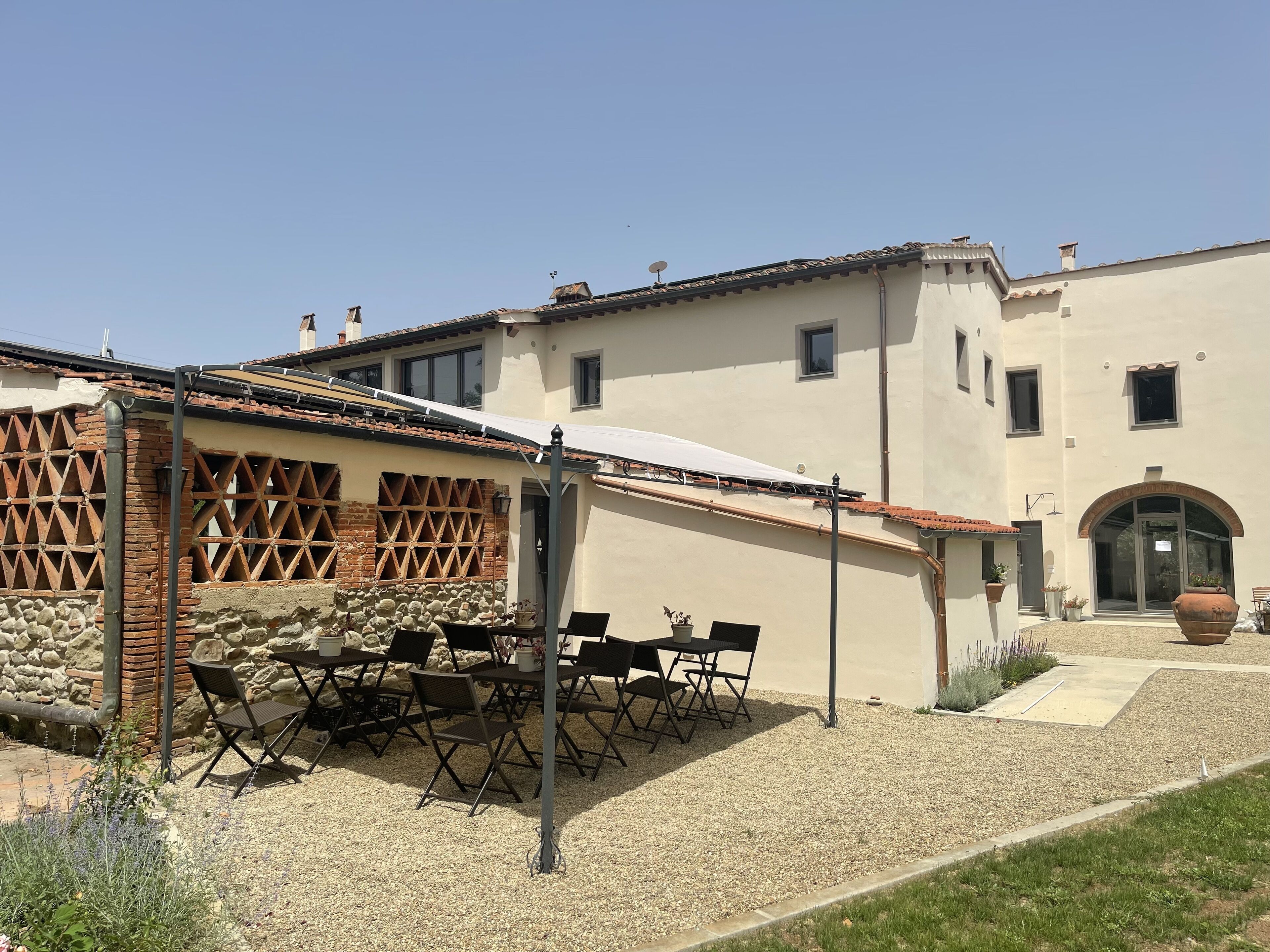 Un edificio con un patio dotato di posti a sedere all'aperto e un muro in pietra.