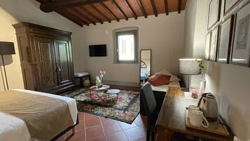 Un dormitorio con cama, un armario de madera, una mesita de noche con lámpara, una silla y una ventana con vistas al exterior.