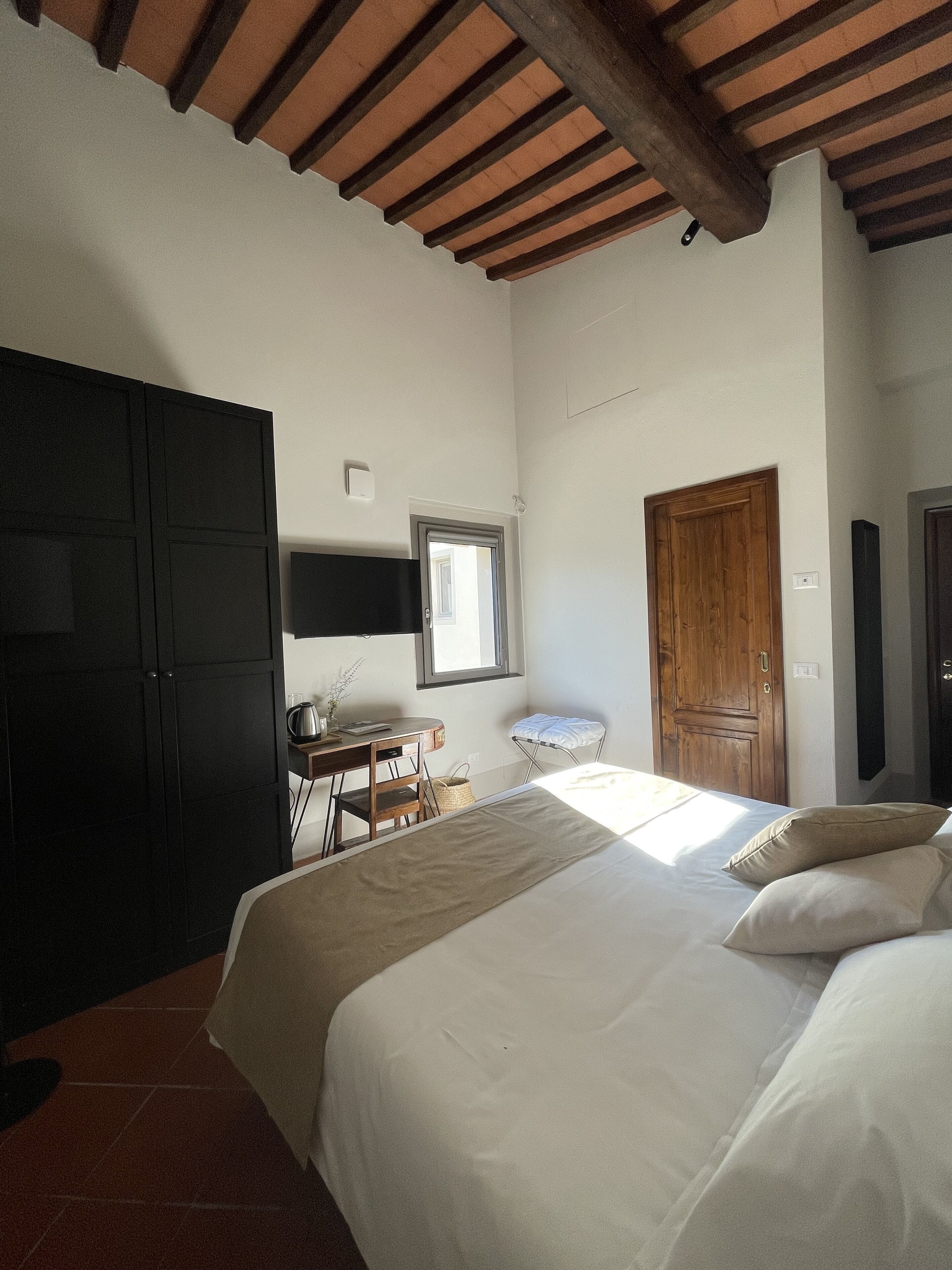 Une chambre à coucher avec un lit, un bureau, une chaise, une armoire et une fenêtre.