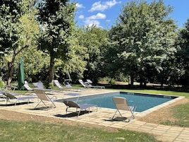 Zona de piscina con sillones de descanso y una piscina.