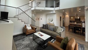 A spacious living area with a staircase leading to an upper level, a dining area, and a kitchen. - Beautiful New 4 Bedroom Home with views Minutes from Arches (Moab)