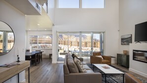 A spacious living area with a large window, a sofa, a coffee table, and a TV. - Beautiful New 4 Bedroom Home with views Minutes from Arches (Moab)
