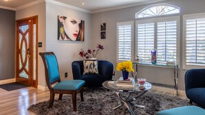 A living room with a blue armchair, a glass coffee table, and a door with stained glass. - 20% Disc-Modern-King Bed, Jacuzzi, Fire Pit, BBQ+ (Los Angeles)