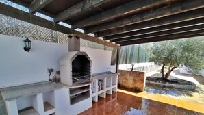 Un'area cucina esterna con forno a incasso, lavello e piano di lavoro in pietra.