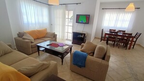 Un soggiorno con due divani, un tavolino, una televisione e un'area pranzo con sedie e tavolo.