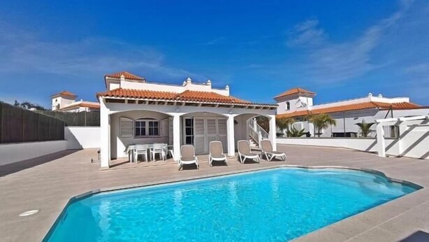A swimming pool with lounge chairs and a covered patio area.