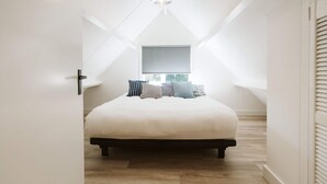 A bedroom with a bed, a window, and a hanging light fixture. - Modern Holiday Home With Spacious Garden and Terrace Suitable for 5 People (Ouddorp)