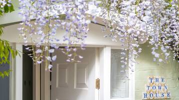 A doorway with a white door, a sign reading 'THE TOWN HOUSE,' and hanging purple flowers.