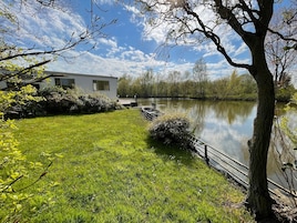 Uma propriedade à beira do lago com gramado, um cais e uma casa com janelas amplas.