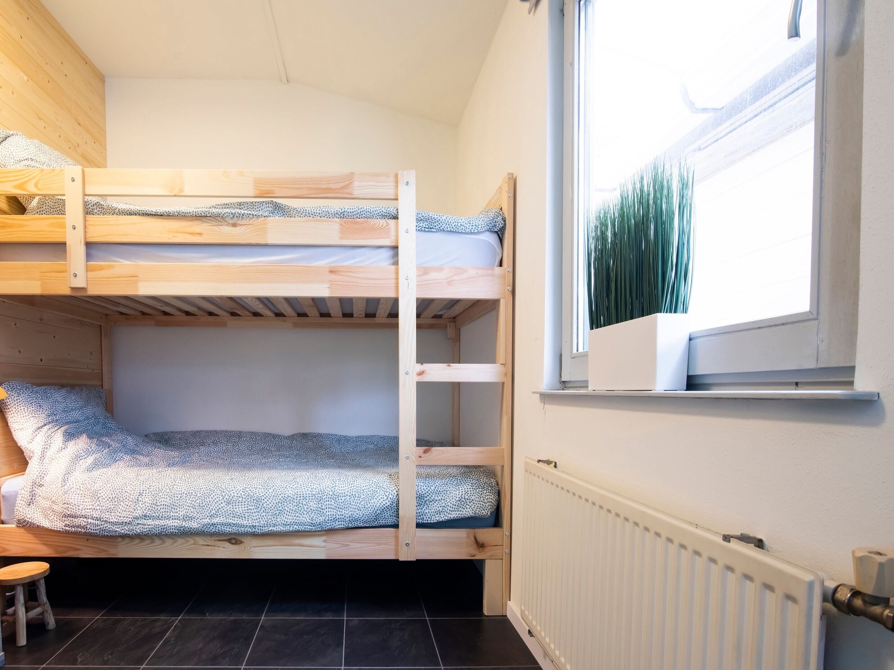 A bunk bed room with a window and radiator.