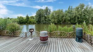 A wooden deck with a view of a river and trees. - Idyllic Holiday Home in Ooltgensplaat on the Water (Ooltgensplaat)