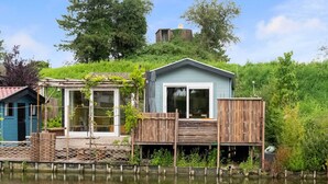 A houseboat with a deck and a small garden area, surrounded by water. - Idyllic Holiday Home in Ooltgensplaat With Private Terrace (Ooltgensplaat)