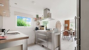 A modern kitchen with a central island, built-in appliances, and a view of the outdoors. - Idyllic Holiday Home in Ooltgensplaat With Private Terrace (Ooltgensplaat)