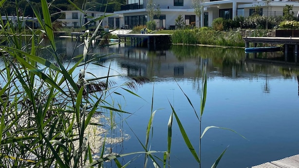 A modern building with a reflective water body in front, surrounded by greenery. - Villa in Harderwold With Garden (Zeewolde)