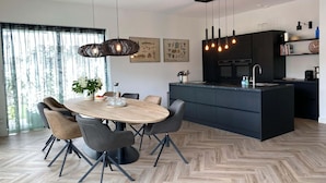 Una cocina moderna con una isla central, muebles oscuros e iluminación colgante.