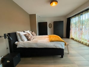 A modern bedroom with a black bed, white bedding, and a yellow throw blanket.