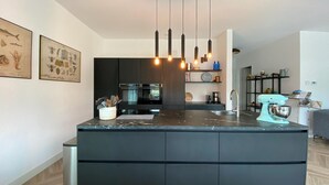Una cocina moderna con una isla central, muebles oscuros e iluminación colgante.