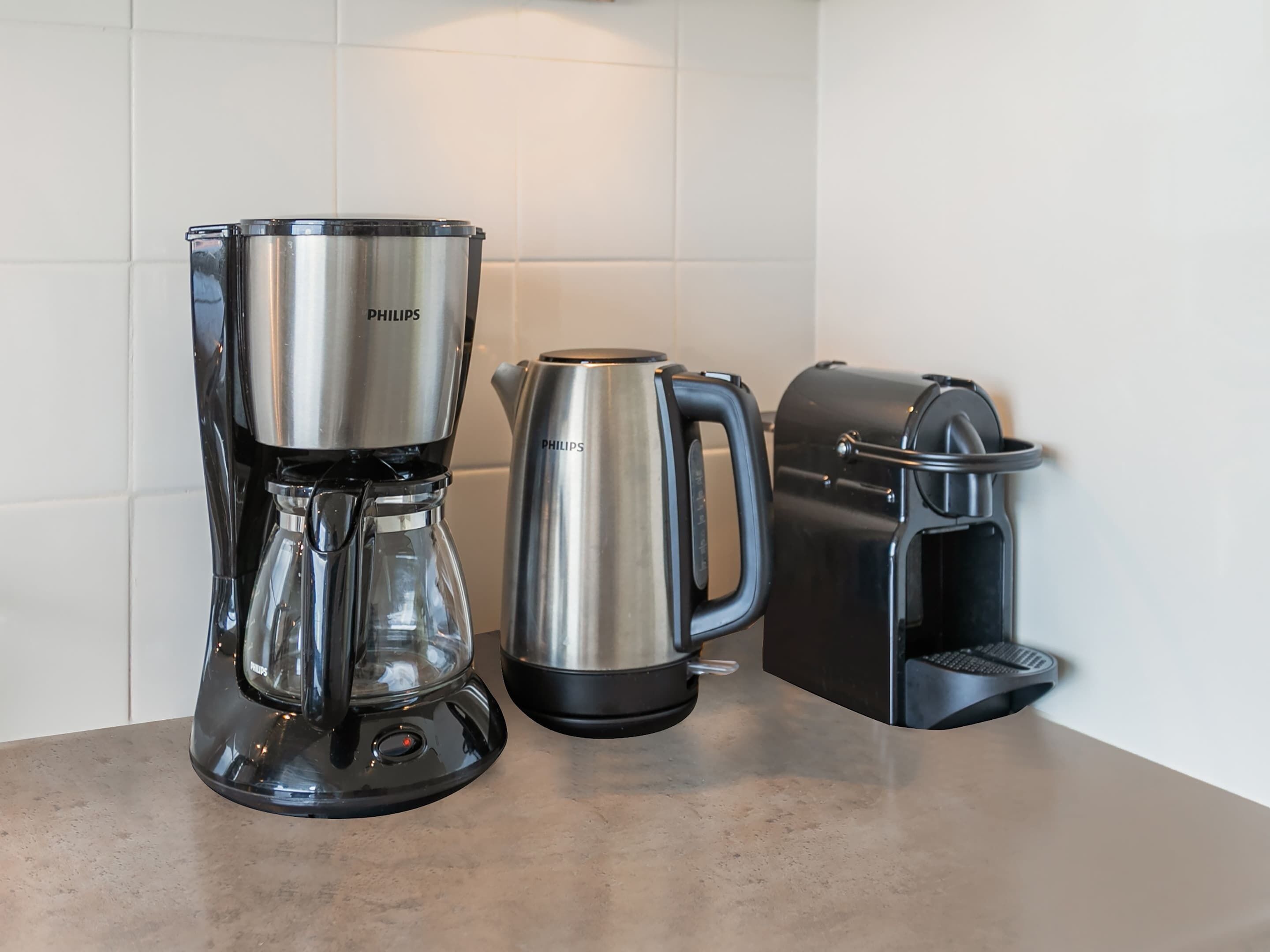A coffee maker, a kettle, and a toaster on a countertop.