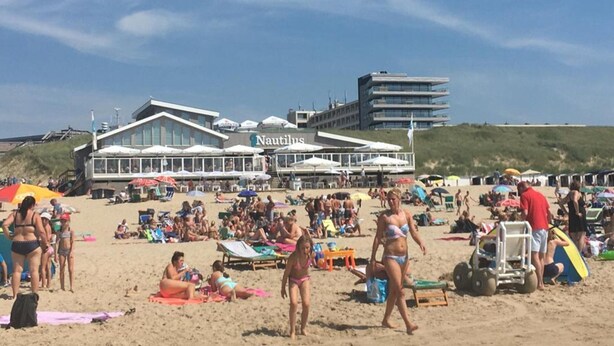 A beachside hotel with a prominent 'Nautilus' sign, outdoor seating, and a sandy beach area with people and beach chairs. - Apartment Near North Sea and Lighthouse (Egmond aan Zee)