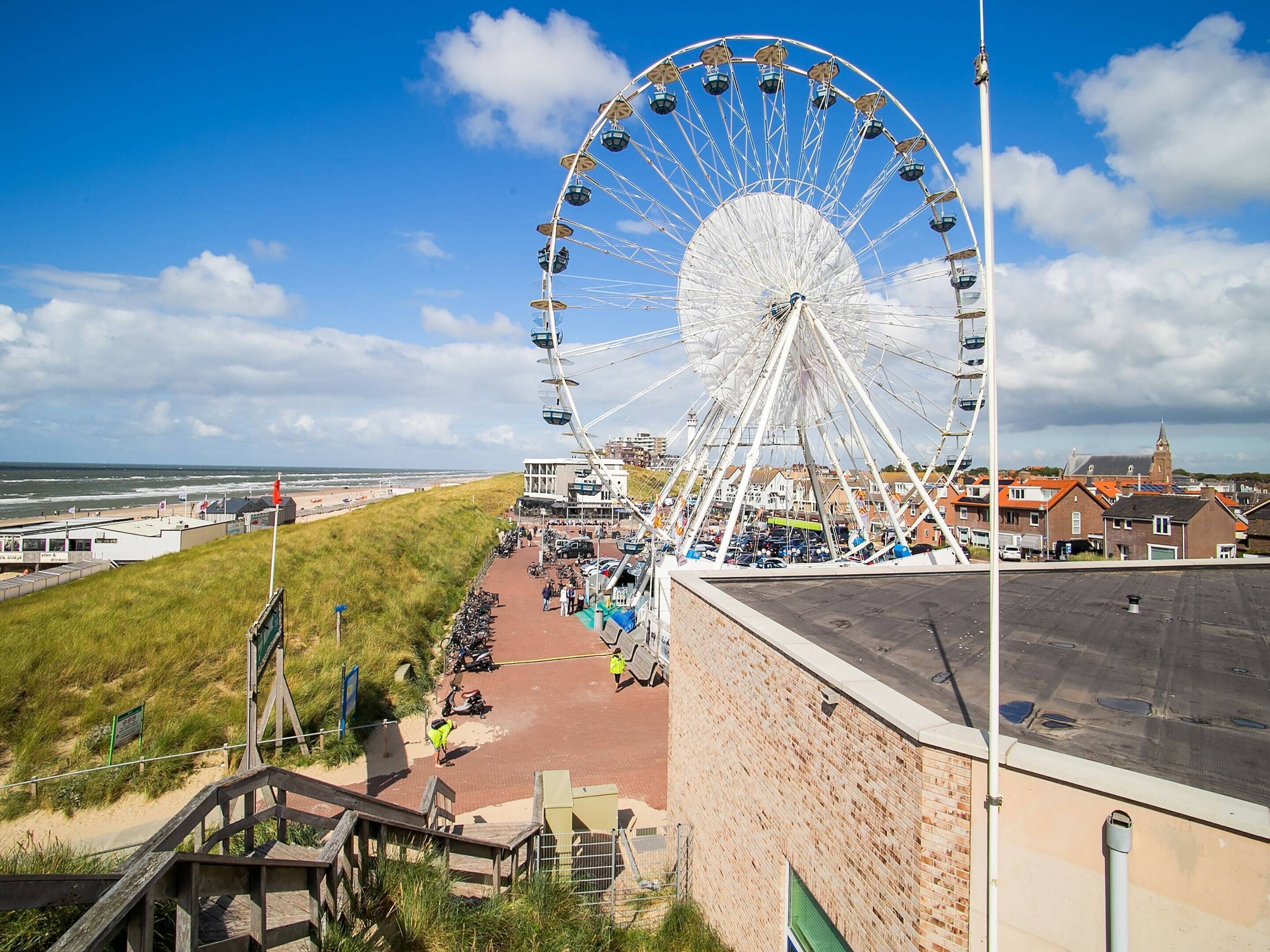 Une grande roue, une plage et un bâtiment à la façade en briques.