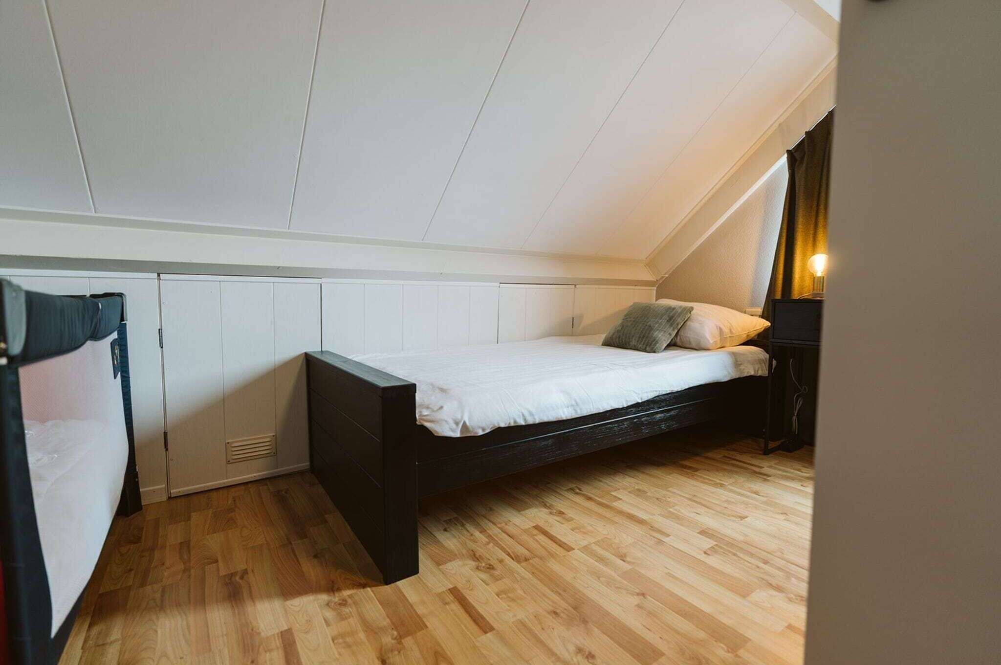 A compact bedroom with a single bed, built-in wardrobe, and a small desk.